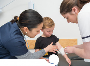 Photo of two nurses wrapping a bandage around a child's arm 